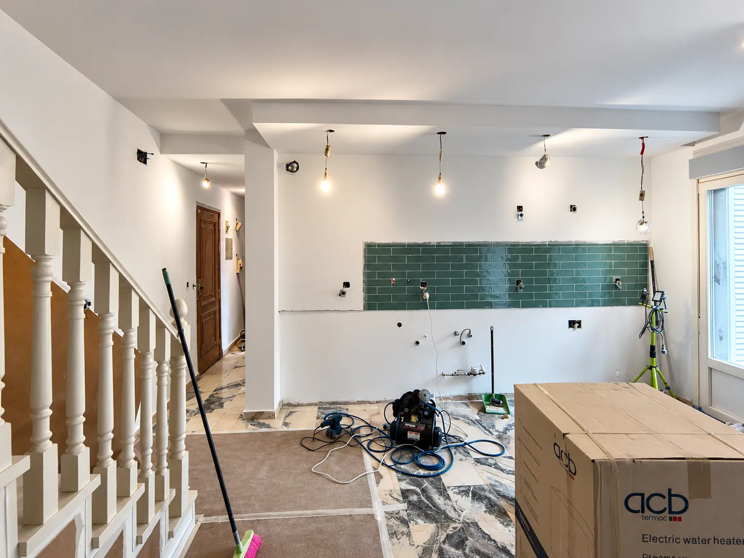 Reforma integral de una vivienda con cocina alicatada en verde y escalera renovada